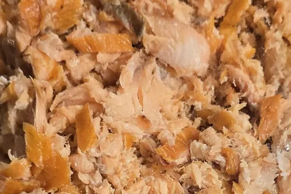 Detail van de grove vlokken en structuur van warmgerookte pulled zalm